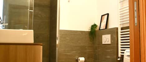 Un baño moderno con tragaluz, tocador de madera, dos inodoros y una lavadora.