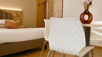 A modern hotel room with a bed, a white chair, a wooden floor, and a wall clock.