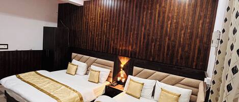 A hotel room with two beds, a ceiling fan, a wooden panel wall, and a nightstand with a lamp.
