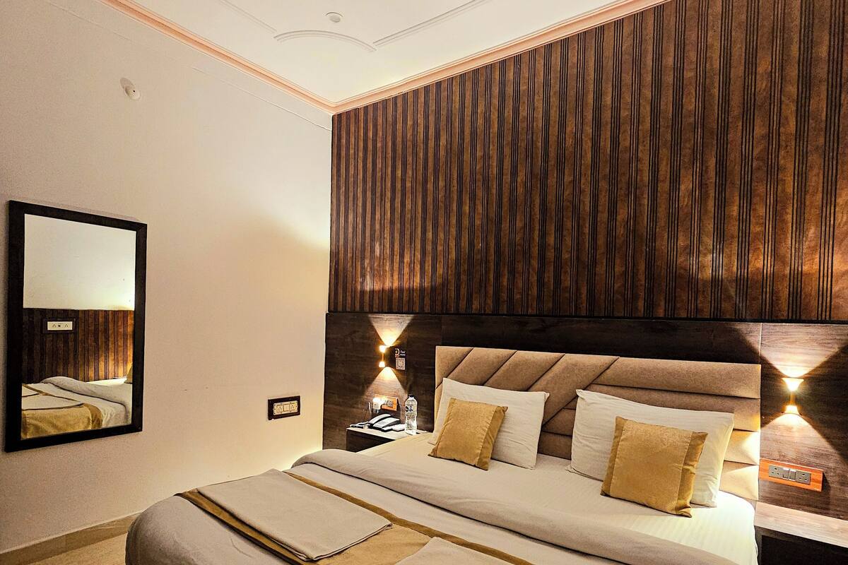 A modern bedroom with a large bed, wooden headboard, and bedside lamps.