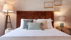A neatly made bed with a brown headboard, multiple pillows, a bedside lamp, and a small bedside table with a lamp and a book. - Pine Tree House in Azeit o (Setubal)