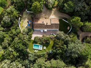 Luchtbeeld van een huis met pannendak, zwembad en omliggend groen.