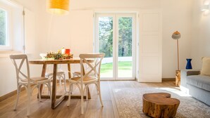 Un espace repas comprenant une table et des chaises, une petite table d’appoint en bois et un lampadaire.