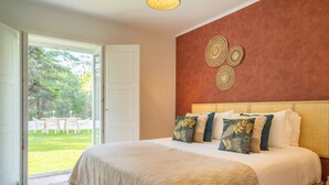 Une chambre avec un grand lit, une vue sur l’extérieur et un mur orné de motifs décoratifs.