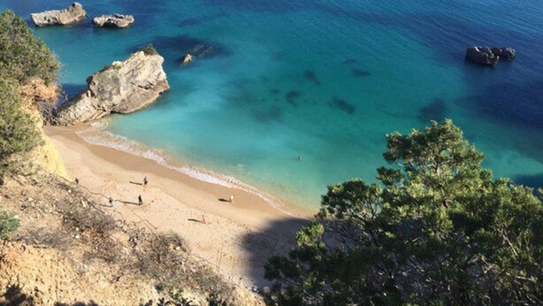 A coastal beach with clear turquoise waters, rocky outcrops, and a sandy shoreline. - Wood Oven House II in Azeit o (Setubal)