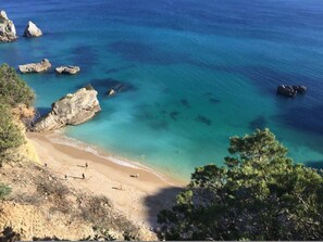 Una spiaggia costiera con acque cristalline color turchese, affioramenti rocciosi e un litorale sabbioso.