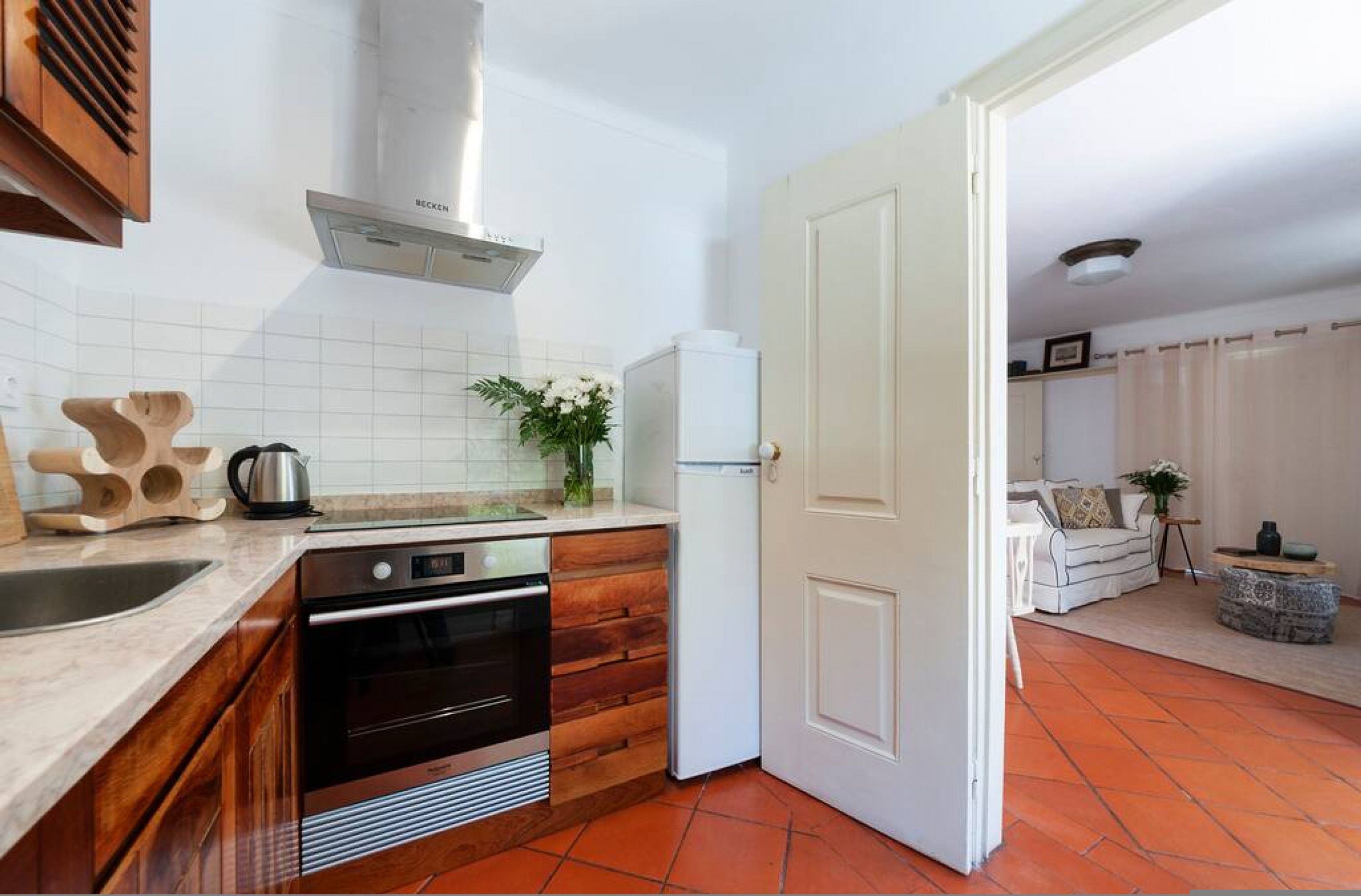 Eine kleine Küche mit Holzausstattung, einem Einbauofen und einem weißen Kühlschrank.