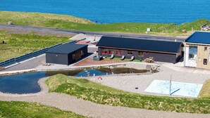 Un bâtiment situé sur la côte, doté d’une piscine, d’un espace extérieur aménagé et offrant une vue sur la mer.