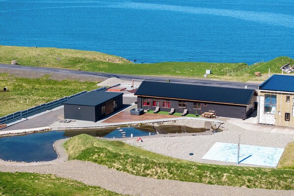 Um edifício costeiro com piscina, área de estar ao ar livre e vista para o mar.