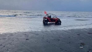 Un véhicule sur une plage, sous un ciel nuageux.