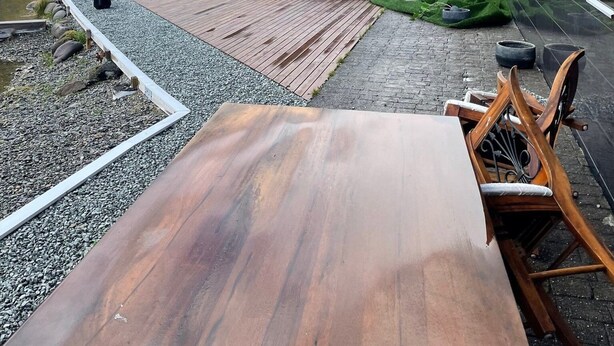 Un espace extérieur moderne, aménagé pour se détendre, avec une table et des chaises en bois, un jacuzzi et une vue sur un paysage montagneux.