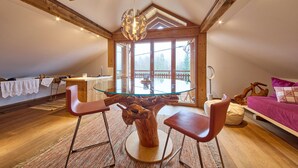 A dining area with a glass table, wooden chairs, and a unique tree stump centerpiece. - Waldharmonie Chalet & Apartments (Bad Goisern)