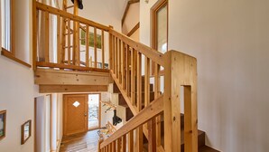 A wooden staircase with a lofted landing, a door leading to an outdoor area, and a colorful striped rug on the floor. - Waldharmonie Chalet & Apartments (Bad Goisern)