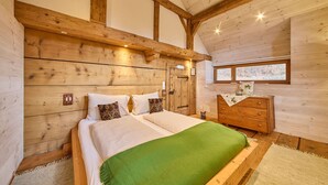 A wooden bedroom with a bed, dresser, and window. - Waldharmonie Chalet & Apartments (Bad Goisern)
