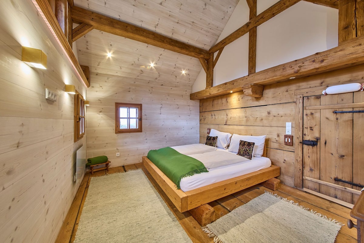 Une chambre dans une cabane en bois, avec un lit, une fenêtre et une porte.