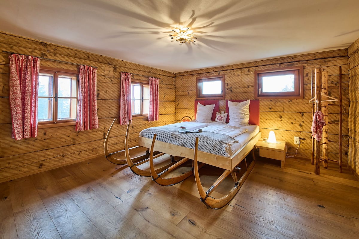 Une chambre dans une cabane en bois, avec un lit, une table de chevet et un fauteuil à bascule.