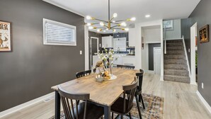 A dining area with a wooden table, chairs, and a chandelier. There is a staircase leading to another level. - Stylish 3BR in Cleveland Hts |  Close to Clinic, UH (Cleveland Heights)