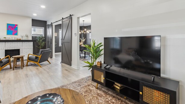 A modern living room with a large flat-screen TV, a fireplace, and a dining area with a table and chairs. - Stylish 3BR in Cleveland Hts |  Close to Clinic, UH (Cleveland Heights)
