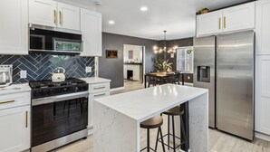 A modern kitchen with white cabinets, a marble island, stainless steel appliances, and a herringbone tile backsplash. - Stylish 3BR in Cleveland Hts |  Close to Clinic, UH (Cleveland Heights)
