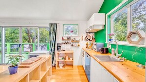 A modern kitchen with wooden countertops, a built-in oven, and a window with a view of greenery. - Sky-High Treehouse | Pool & Hot Tub! (Austin)