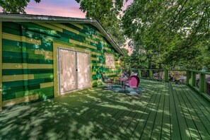 A green wooden deck with a covered seating area and a door.