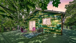 A small cabin with a porch, two chairs, and a table. - The Hartyard | 3 Houses! | Pool & Hot Tub (Austin)