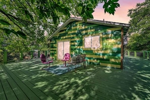 Eine kleine Holzhütte mit Veranda, zwei Stühlen und einem Tisch.