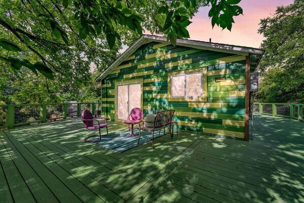 A small cabin with a porch, two chairs, and a table.
