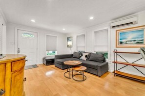 A modern living room with a grey sofa, a wooden coffee table, and a wooden cabinet.