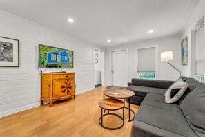 Ein Wohnzimmer mit einer Couch, einem Holzschrank und einem Fernseher an der Wand.
