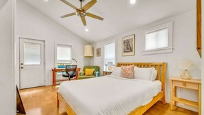 A bedroom with a bed, a desk, a chair, a ceiling fan, and a window. - The Hartyard | 3 Houses! | Pool & Hot Tub (Austin)