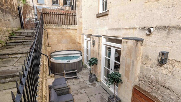 A courtyard with a hot tub, outdoor seating, and potted plants.
