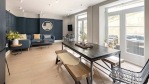 A modern living room with a dark blue sofa, a round mirror, and a wooden coffee table.