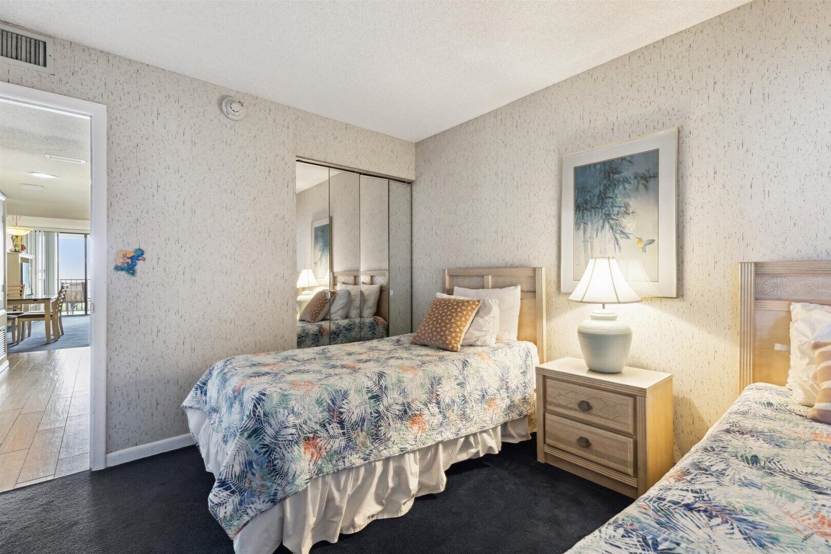 Een slaapkamer met een bed, nachtkastje en spiegel.