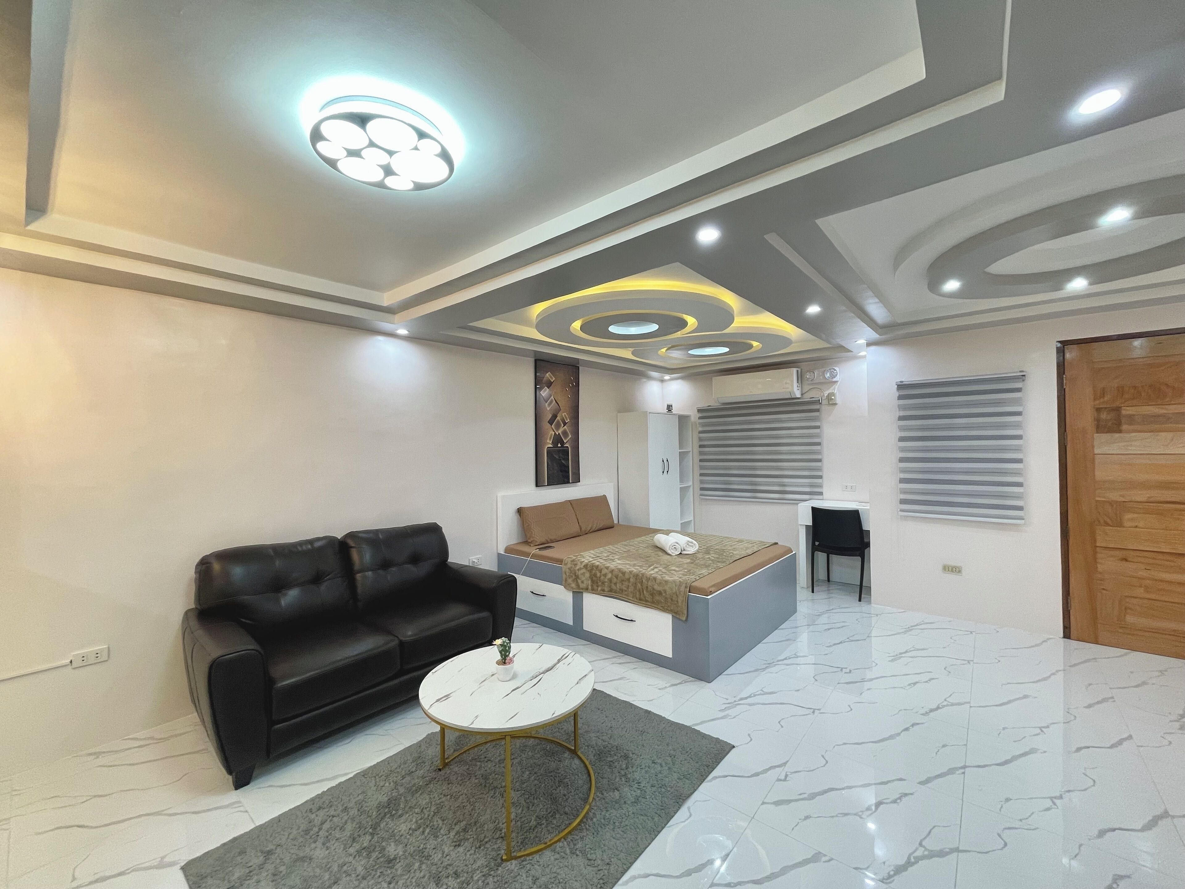 A modern bedroom with a bed, a sofa, a desk, and a chair.