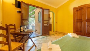 A room with a bed, a table with chairs, a TV, and a door leading to an outdoor area.