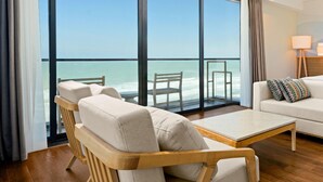 A modern hotel room with a large balcony, a wooden ceiling fan, and a white sofa.
