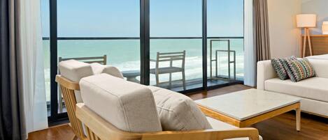 A modern hotel room with a large balcony, a wooden ceiling fan, and a white sofa.