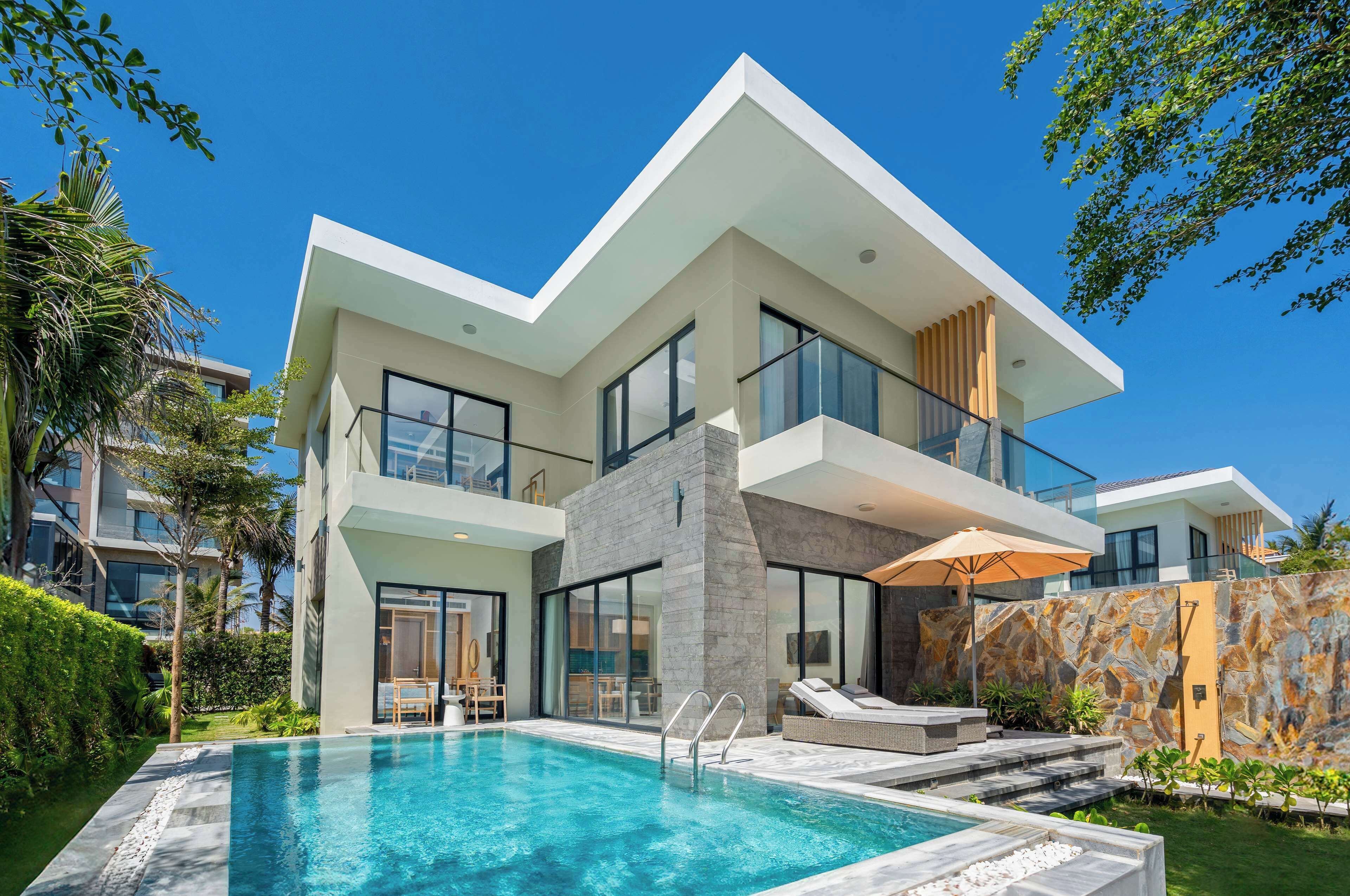 A modern two-story house with a swimming pool, large windows, and a stone facade.