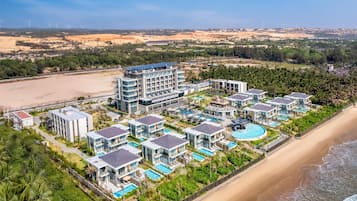 Enjoy beachfront relaxation and water activities at this resort, surrounded by lush greenery and multiple pools.