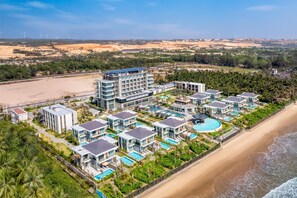 A coastal hotel with multiple modern buildings, a large swimming pool, and a beach view. - Radisson Resort Mui Ne (Mui Ne)