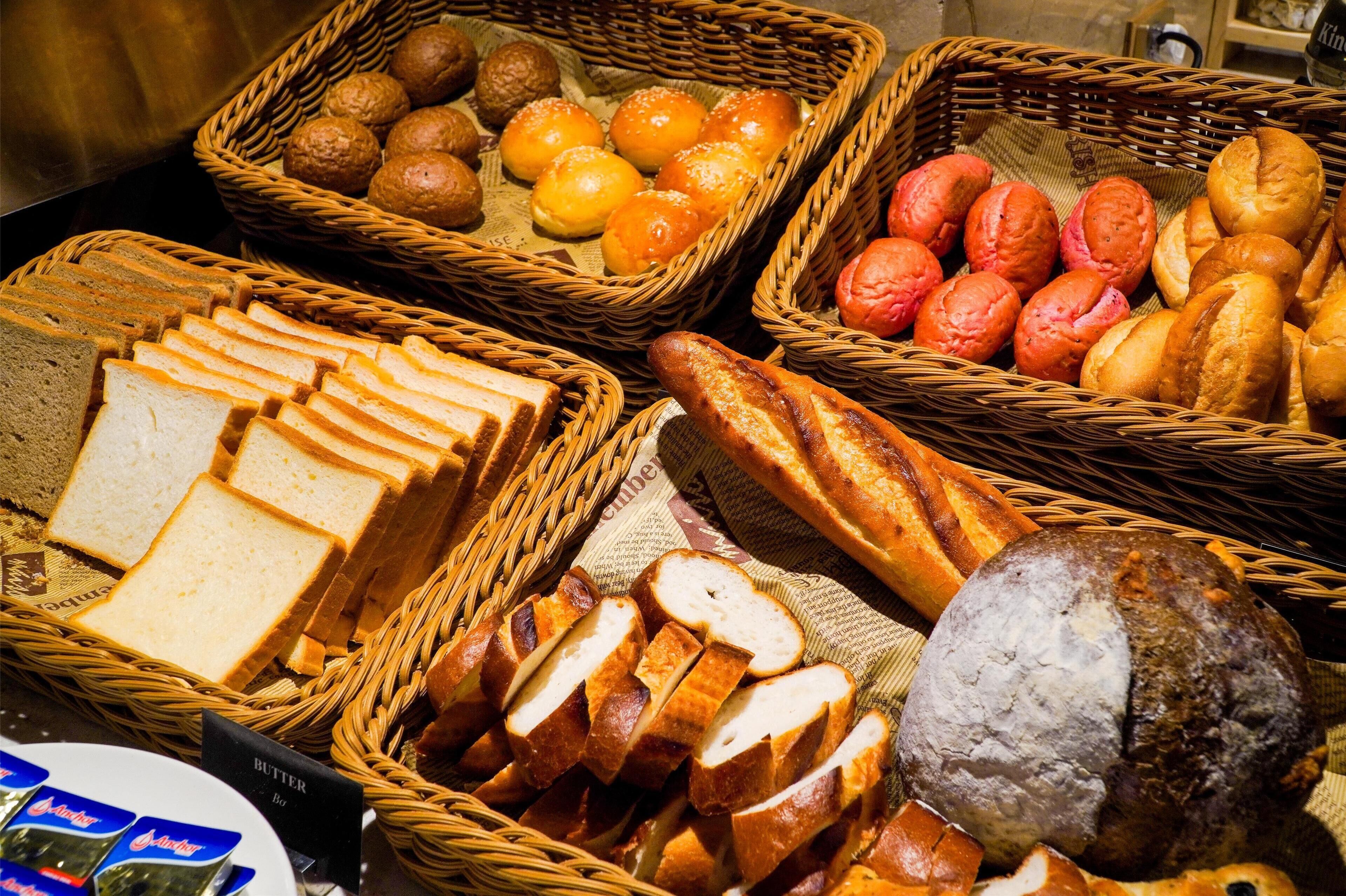 A variety of breads and pastries displayed in wicker baskets.