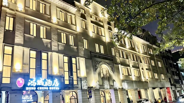 A multi-story hotel with illuminated signage, including 'Hong Cheng Hotel,' and a classical architectural style with columns and arches. - Guangzhou Hongcheng Hotel  (Guangzhou)