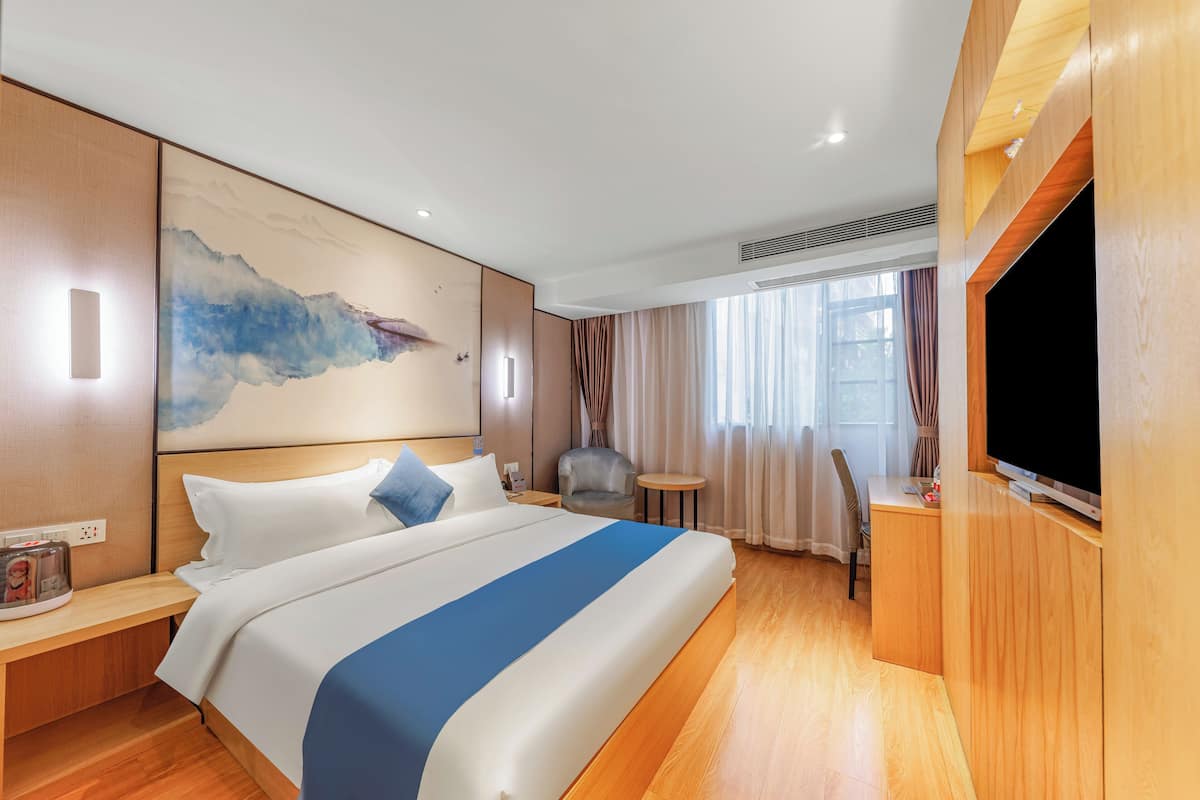 Habitación de hotel con una cama grande, un escritorio, un televisor de pantalla plana, una silla y una mesita.