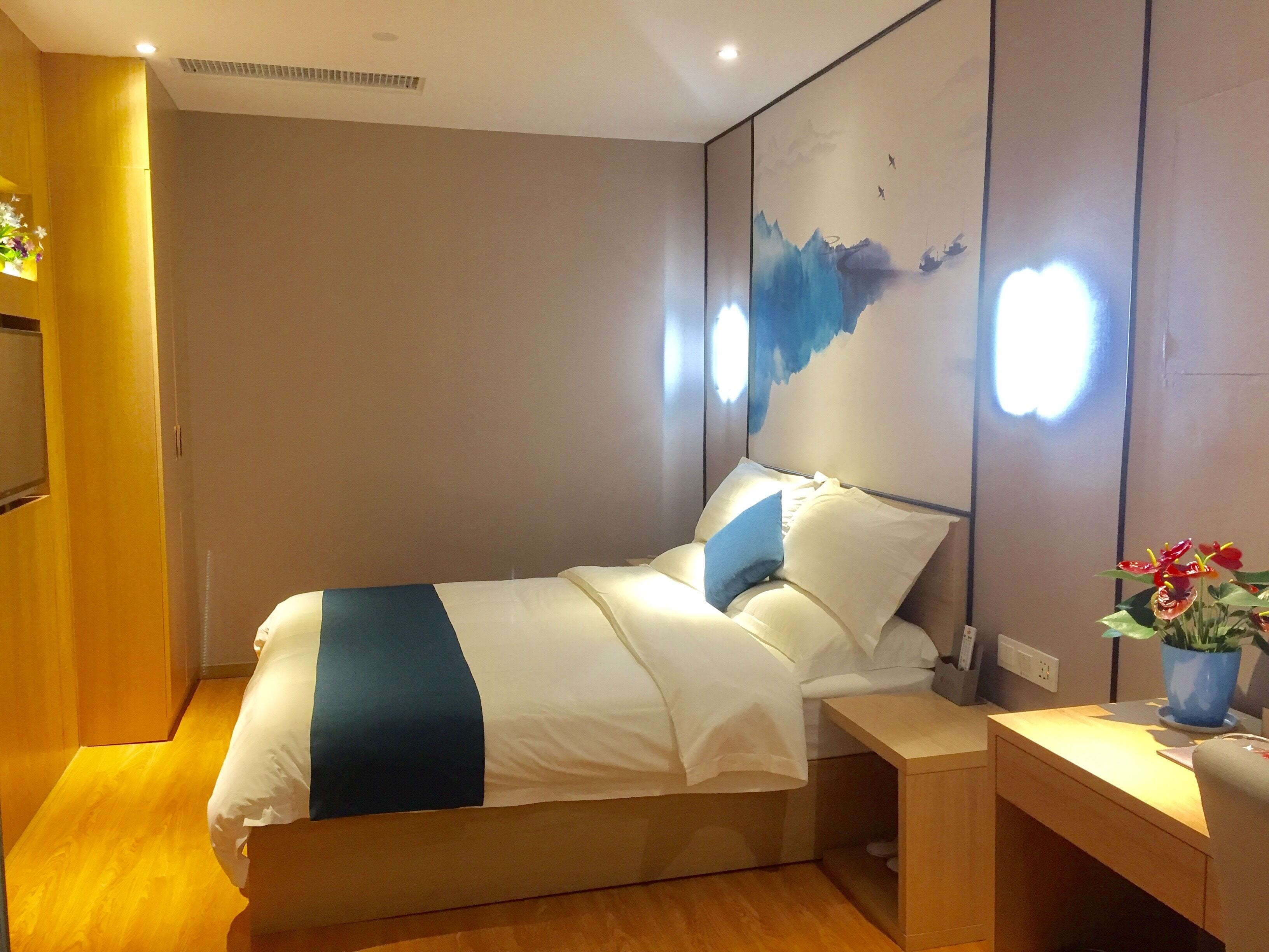 Une chambre d’hôtel avec un lit, une table de chevet et une œuvre d’art accrochée au mur.