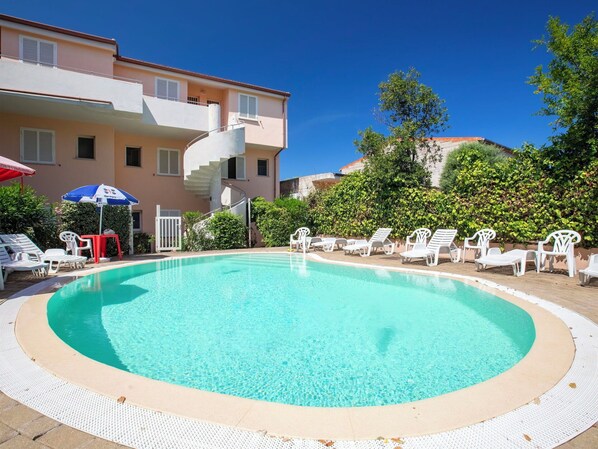A swimming pool with lounge chairs and a staircase leading to a building.