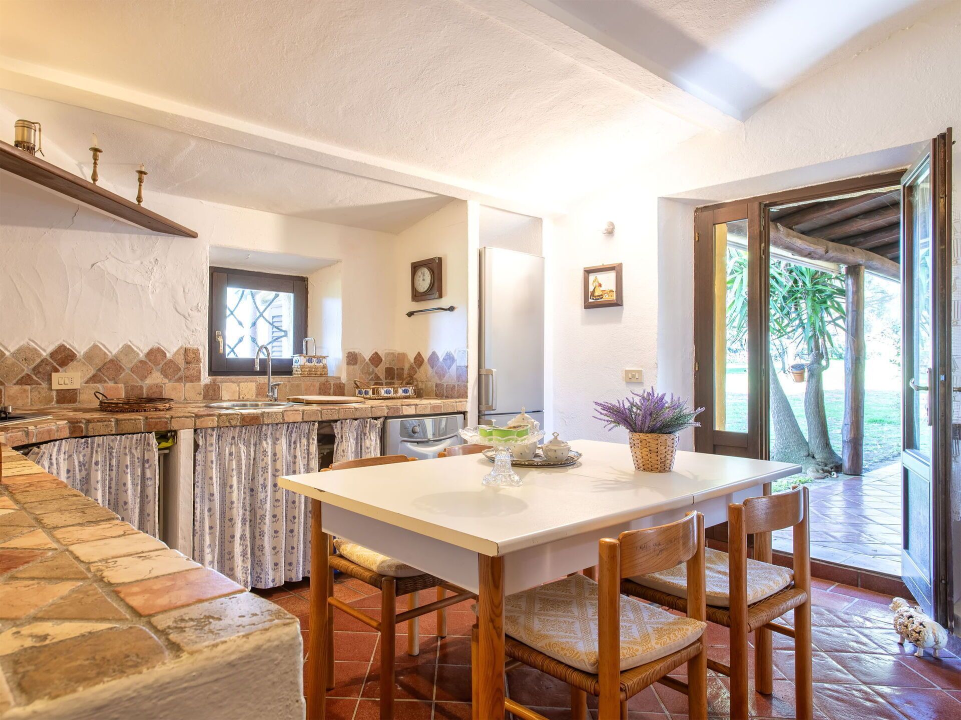 Una cocina con salpicadero de piedra, una mesa de comedor con sillas y vistas al exterior.
