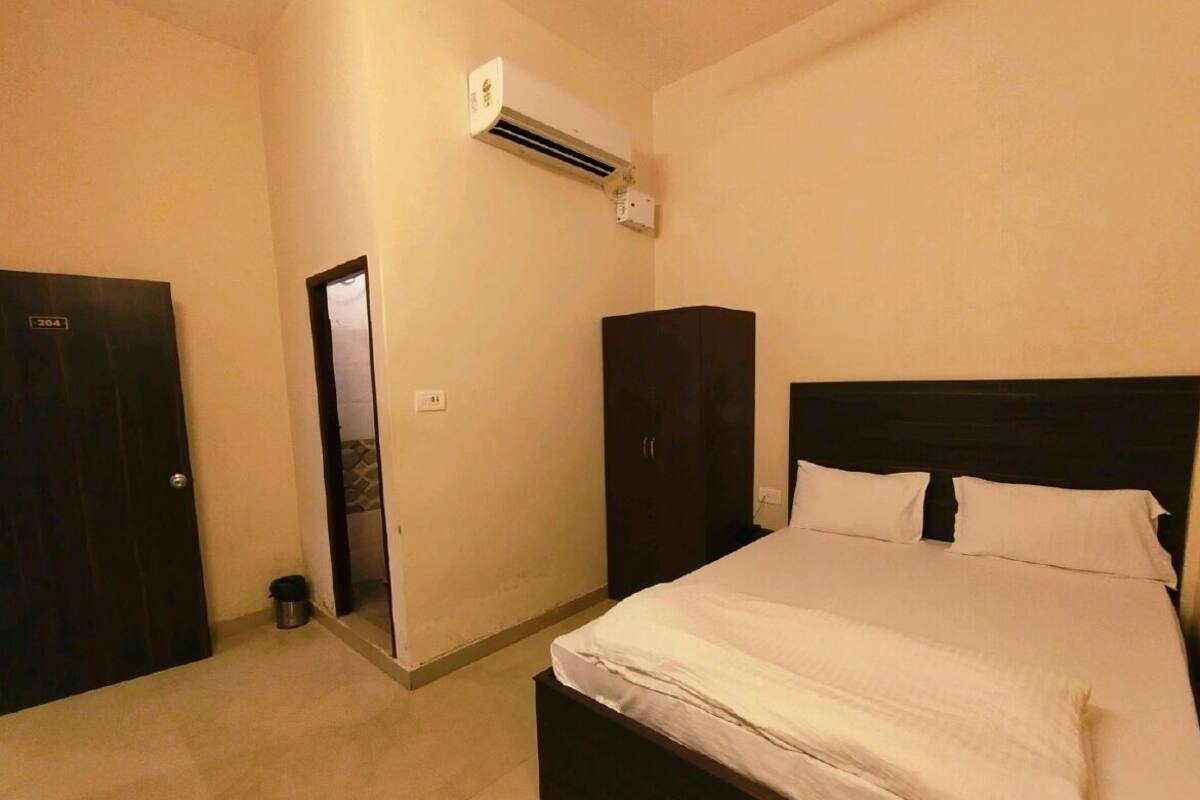 A bedroom with a bed, a wardrobe, an air conditioning unit, and a door.