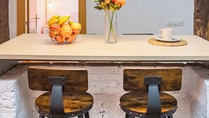 A kitchen area with a white countertop, a fruit bowl, a vase with flowers, and two bar stools. - ☀️❤️Historic penthouse in the heart of Santander ! ❤️☀️ (Santander)