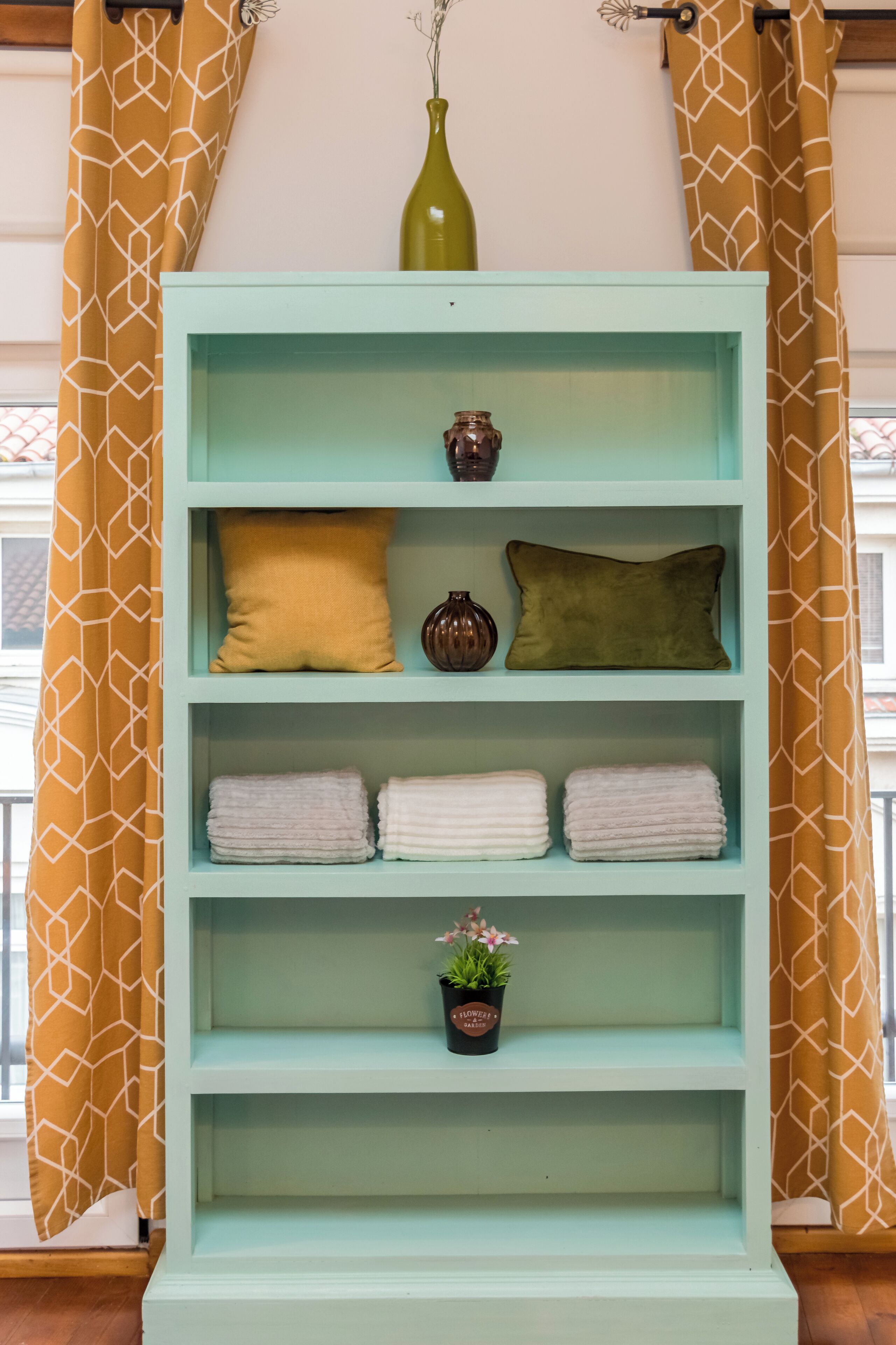 Una estantería color aguamarina con objetos decorativos y toallas.